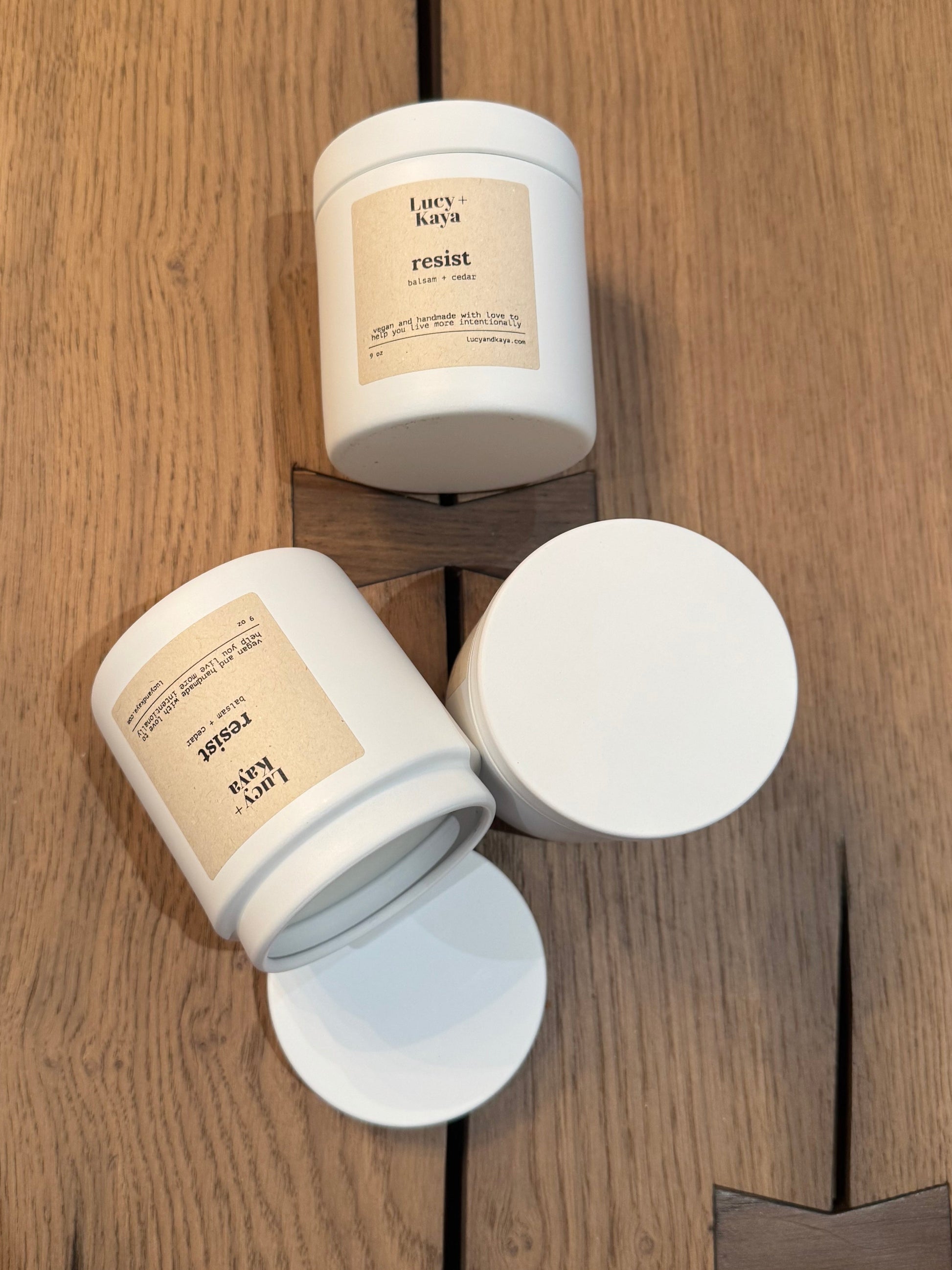 Three white candles with labels on a wooden surface